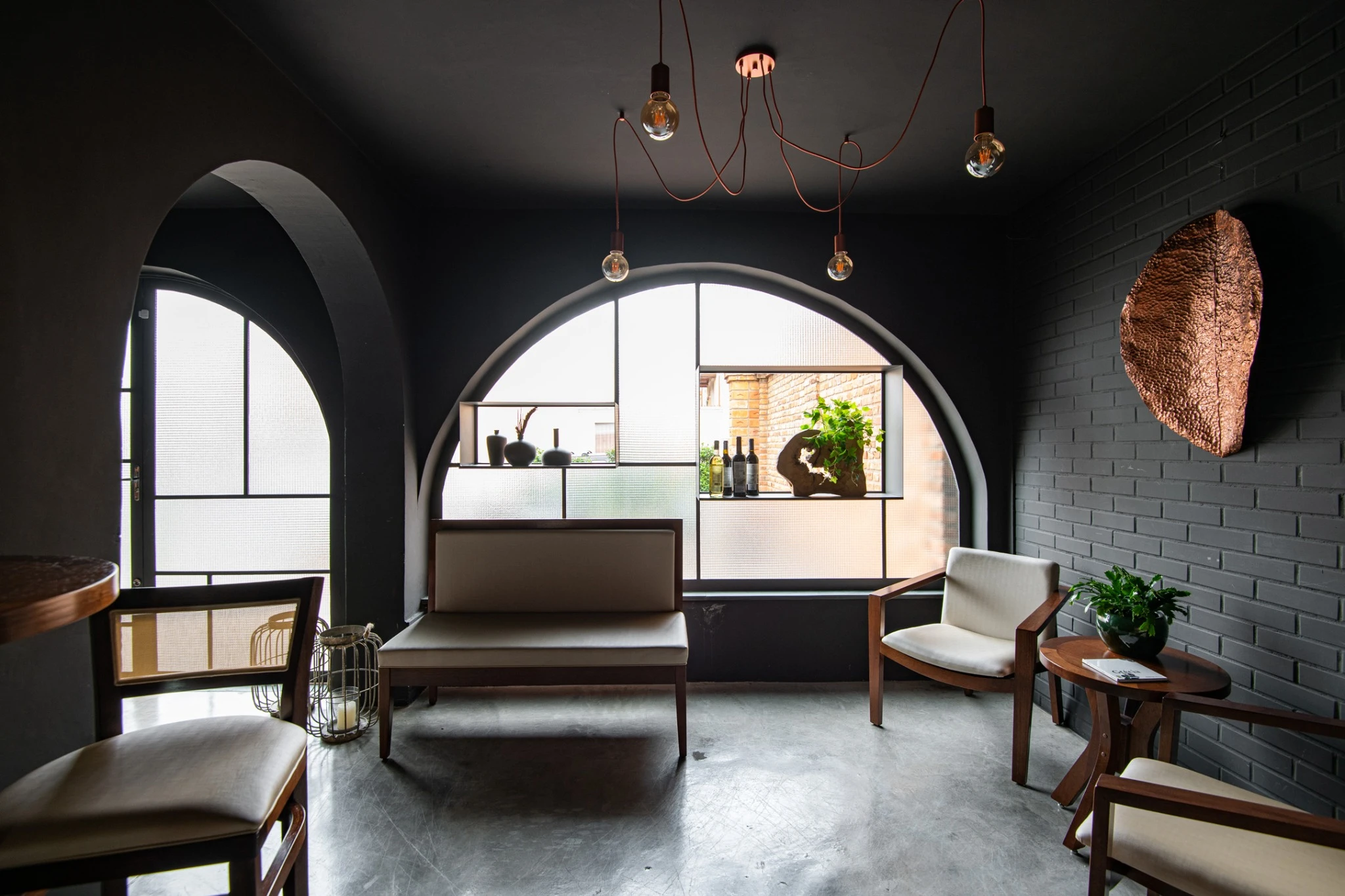 Interior do Albero Ristorante com aberturas em arco, tijolos escuros e mobiliário de madeira