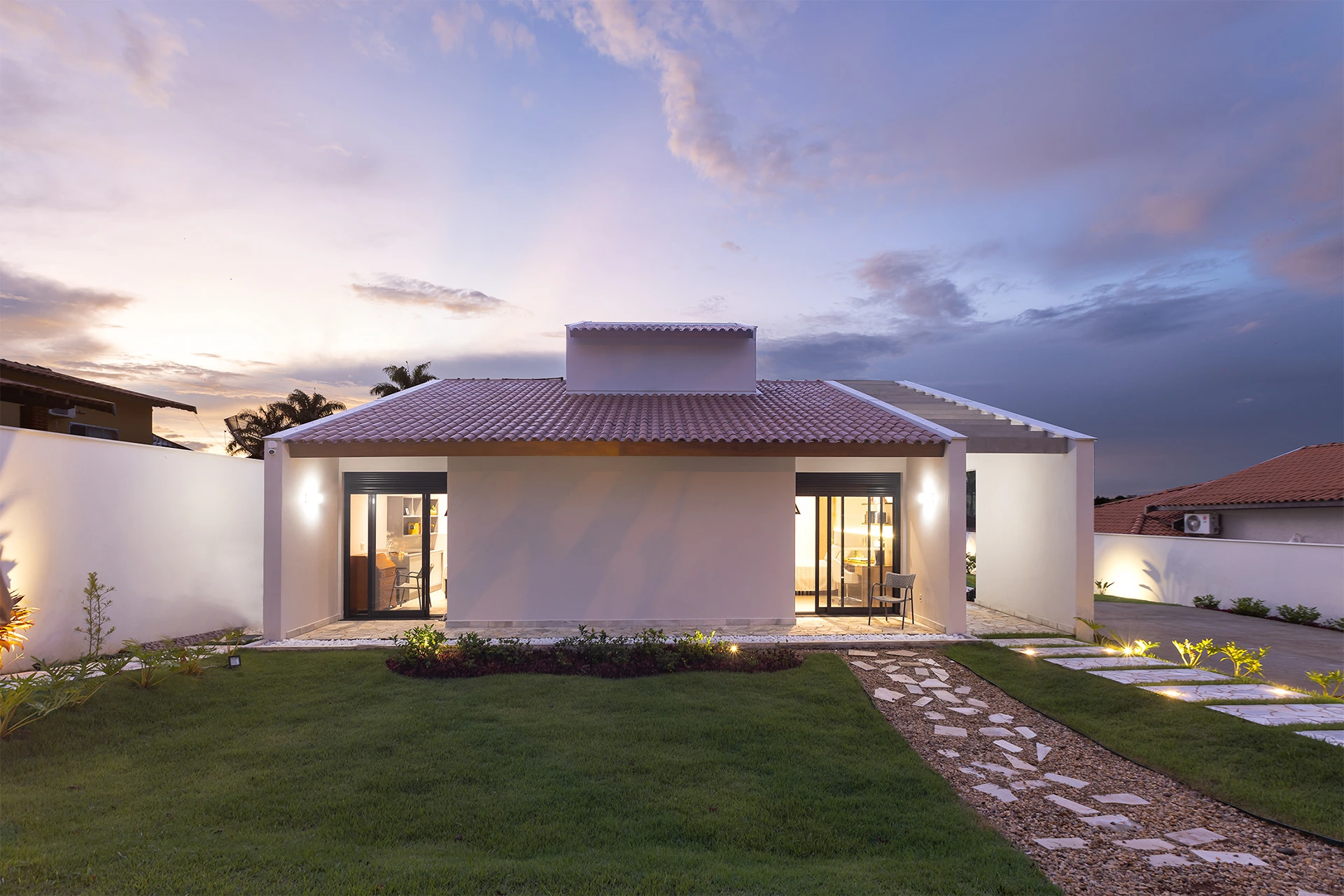 Casa Colinas ao entardecer, com telhado cerâmico, varandas e jardim