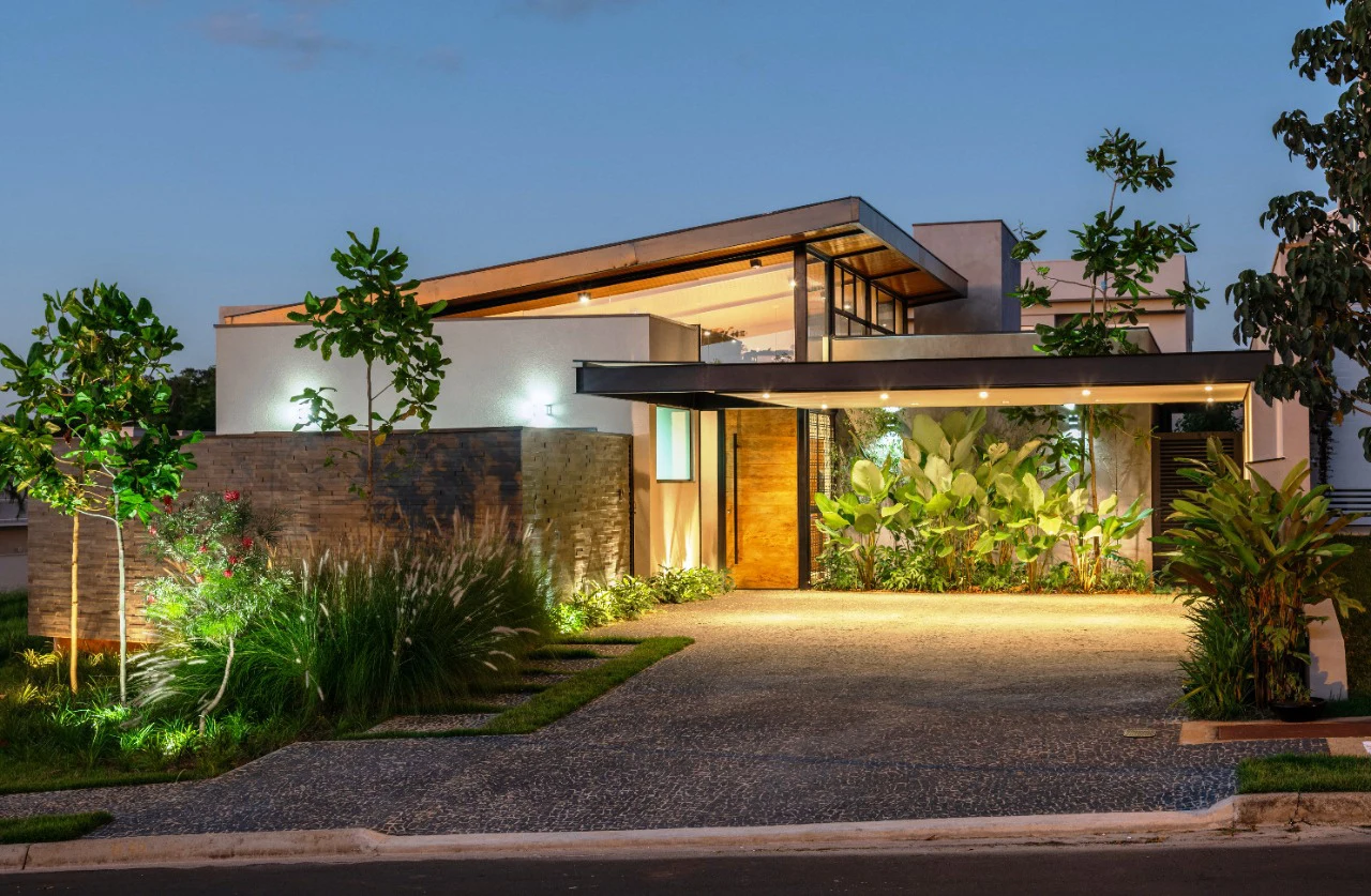 Casa Greville ao entardecer, com cobertura metálica elevada e fachada de pedra